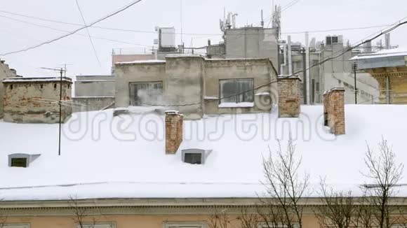 吸烟管在寒冷的冬天采暖季节烟囱在屋顶上下雪视频的预览图
