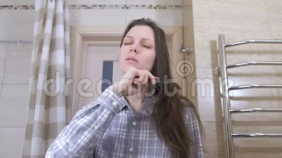 疲惫的醒了的女人梳头站在浴室的镜子前视频的预览图