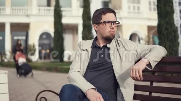 一个戴眼镜的人坐在长凳上呼吸新鲜空气视频的预览图