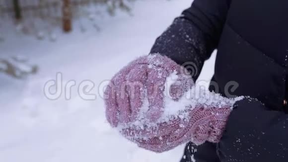冬天的女人编织手套做雪球扔雪球冬天的衣服慢动作的雪冬天的游戏和乐趣视频的预览图