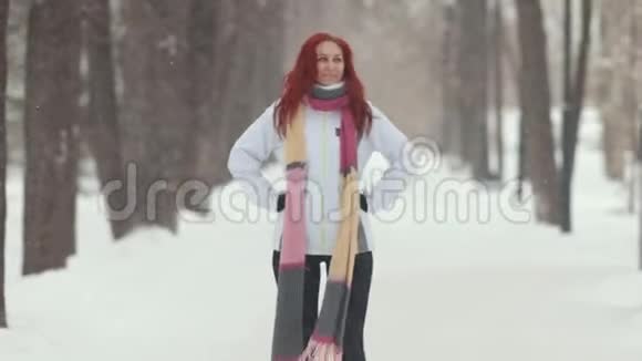 冬季公园站在人行道上的一个红头发的女人跳跃视频的预览图