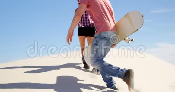 在沙漠中男人和女人用沙板行走视频的预览图