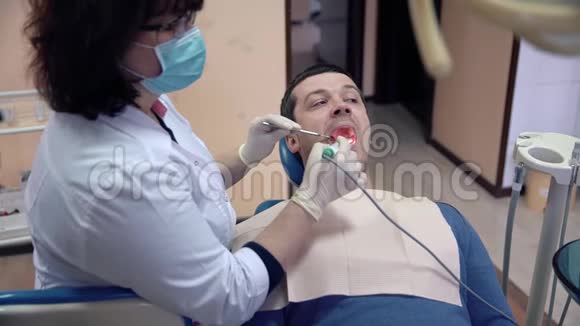 一位女牙医用口腔内摄像机检查一位病人的牙齿并将结果显示在监视器上治疗视频的预览图
