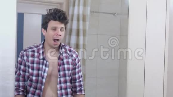 早上一个宿醉的困乏男人在浴室里打哈欠系好衬衫整理好自己视频的预览图