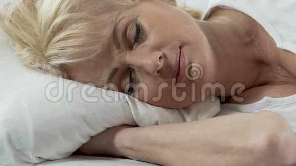 头高的女人躺在枕头上脸上轻笑不受打扰地睡觉视频的预览图