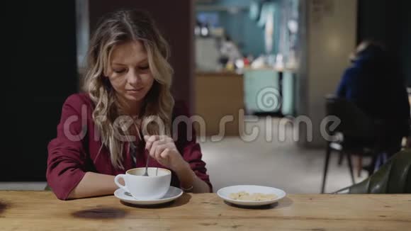美丽的年轻女人卷发喝着咖啡微笑着倾听着视频的预览图