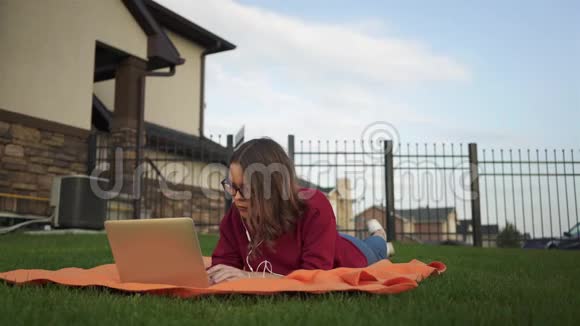 少女拿着笔记本电脑躺在草地上视频的预览图