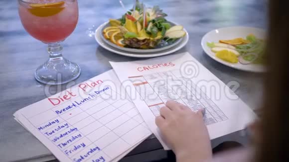 营养学家女士写饮食计划桌上放着食物卡路里盘子里放着饮料和水果视频的预览图