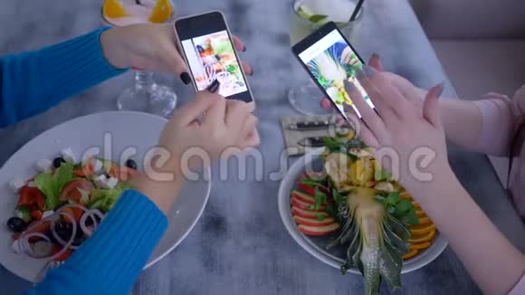 在美味的减肥午餐期间女孩们用手机看美丽食物的照片视频的预览图