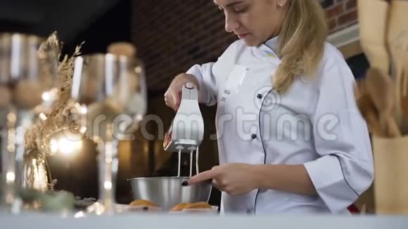 女性糖果师用电动搅拌器在碗中混合白蛋霜视频的预览图