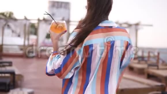 一位奢华时尚的女士端着一杯鸡尾酒走着穿着木制的彩色丝绸礼服视频的预览图