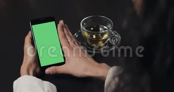 年轻的商务女性使用绿色屏幕的智能手机触摸屏上黑色智能手机绿色屏幕使用智能手机视频的预览图