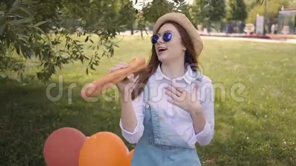 在公园里一个年轻的生姜女孩用布袋作为麦克风唱歌视频的预览图