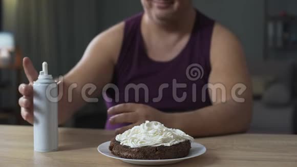 身材魁梧的男人用生奶油装饰巧克力蛋糕不健康的食物视频的预览图