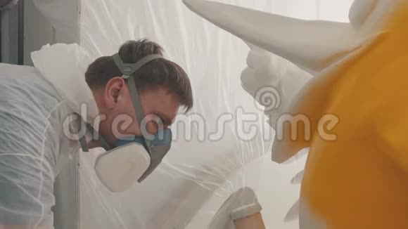 戴防毒面具的人用喷雾器涂油漆视频的预览图