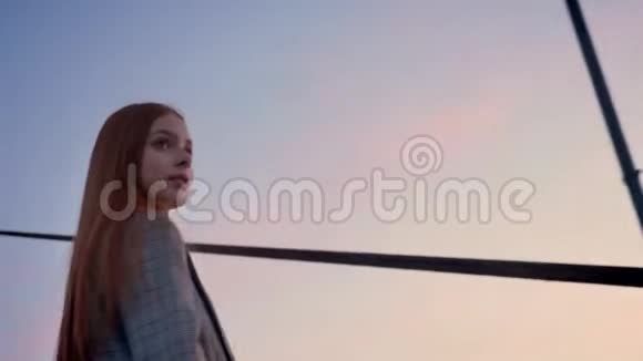 年轻美丽的女人长着一头姜黄色的头发正对着镜头转过身蓝天在上面盘旋视频的预览图