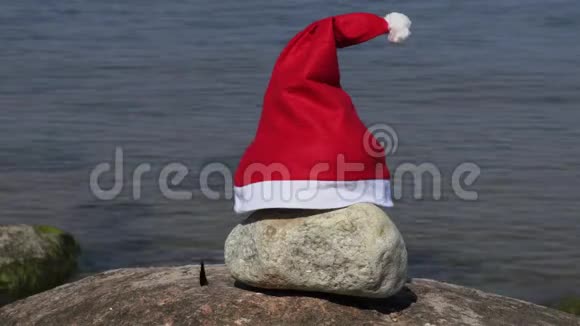 圣诞老人帽子和五颜六色的蝴蝶在海边的石头上视频的预览图