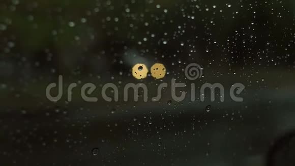 模糊的汽车轮廓透过水滴在汽车挡风玻璃上视频的预览图