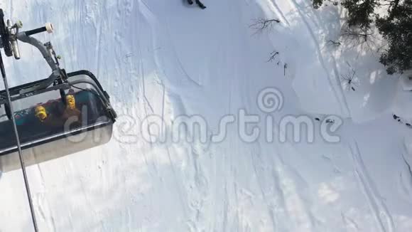 在雪坡背景下人们坐在其中的一个移动的圆形的空中俯视录像雪地缆车视频的预览图
