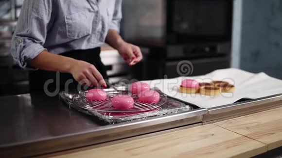 在现代厨房工作的糖果女人准备现代的法国甜点摩丝和粉红色的镜面釉视频的预览图