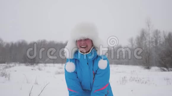 快乐的女人在森林里用手扔雪雪落在阳光下闪闪发光女孩在冬天玩耍视频的预览图