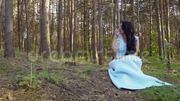 穿着蓝色长裙的美女在森林里吃苹果视频的预览图