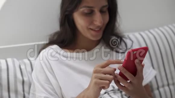 一个年轻漂亮的黑发女人在手机上印着文字视频的预览图