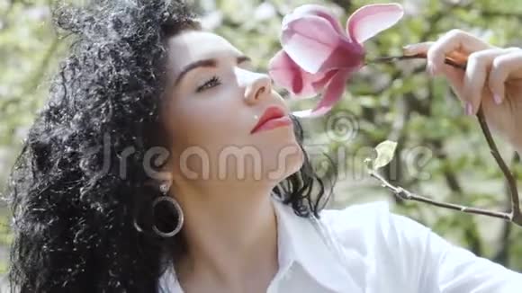 迷人的卷曲黑发欣赏木兰花的气味视频的预览图