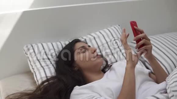 一位年轻女子正在手机上写字一位女士躺在床上视频的预览图
