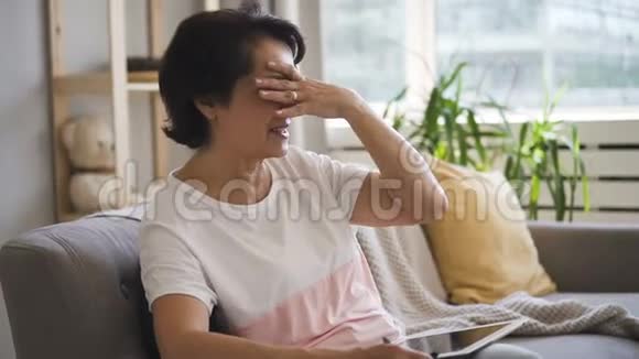 相当成熟的女士正在说话打手势坐在现代公寓的沙发上视频的预览图