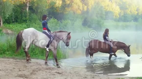 两个美丽的年轻女子两匹马在黎明时在湖里游泳视频的预览图