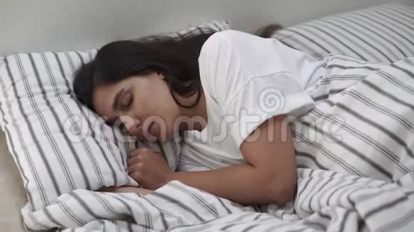 一个年轻的女人躺在床上头靠在枕头上睡觉视频的预览图