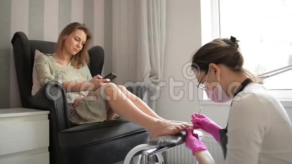 美丽的女人在水疗美容沙龙获得专业教育师父正在清洗她的指甲客户正在聊天视频的预览图