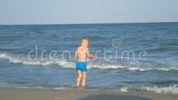 一个小男孩从海滩上的海浪中逃跑视频的预览图