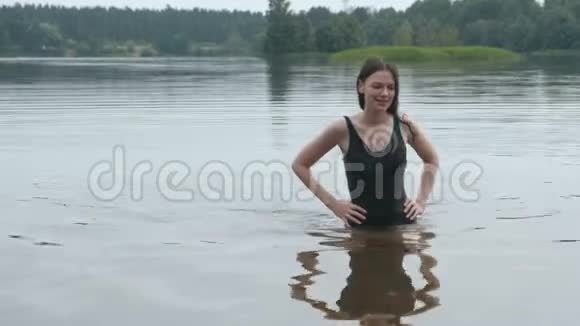 美丽的黑发女人在池塘里游泳微笑着森林中池塘的美丽景色视频的预览图