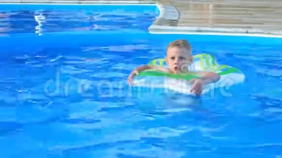 小男孩漂浮在蓝色游泳池的充气圈上视频的预览图