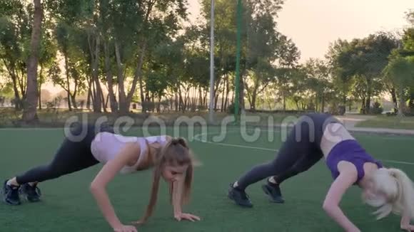 两名年轻女子在公园的足球场上伸展身体减肥健身模特运动视频的预览图
