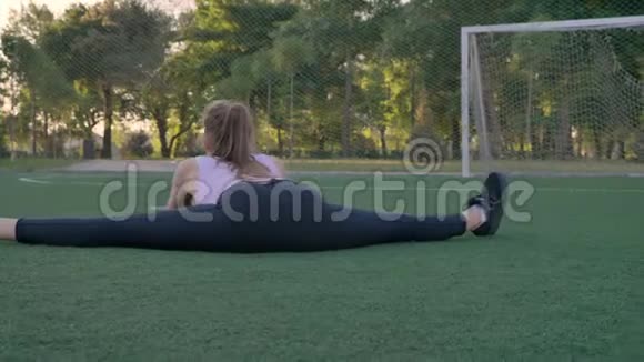 年轻漂亮的女人坐在公园里的空地上晨练减肥视频的预览图