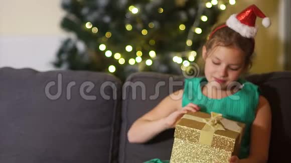 女学生穿着优雅的绿色连衣裙头戴圣诞帽打开礼物女孩非常惊讶视频的预览图