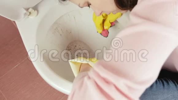 特写女士她的手在黄色橡胶手套用海绵清洗厕所上景视频的预览图