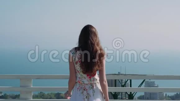 美丽的白种人女孩在城市的一个露台上与海相望视频的预览图