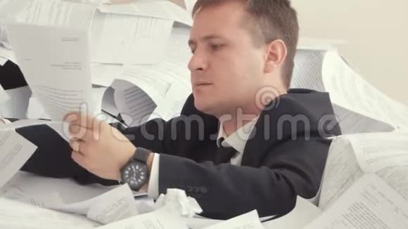 员工因文件堆积如山而抑郁一个疲惫的雇员正坐在一堆文件里视频的预览图