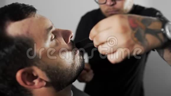 理发师在理发店用修剪机和梳子剪顾客的胡子男士理发和刮胡子视频的预览图