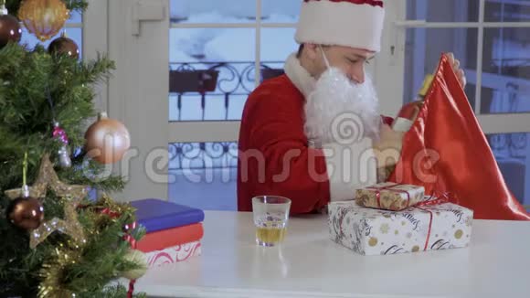 圣诞老人在带礼物的红包里发现了一瓶白葡萄酒视频的预览图