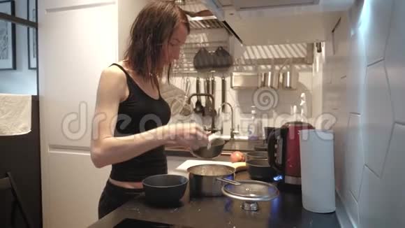 年轻女子站在厨房的炉子旁为家人准备早餐生活方式视频每天视频的预览图
