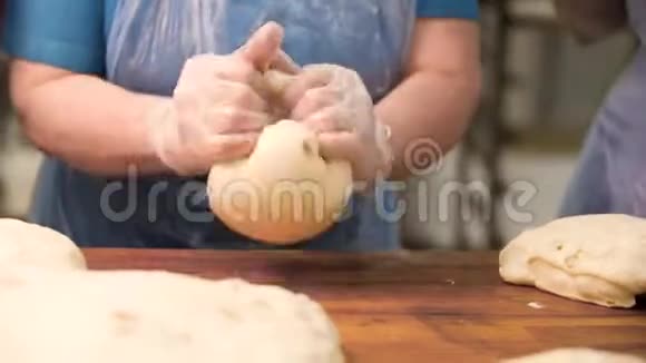 女人在烹饪手套上揉面在木板上食物准备的概念库存录像双手合拢视频的预览图