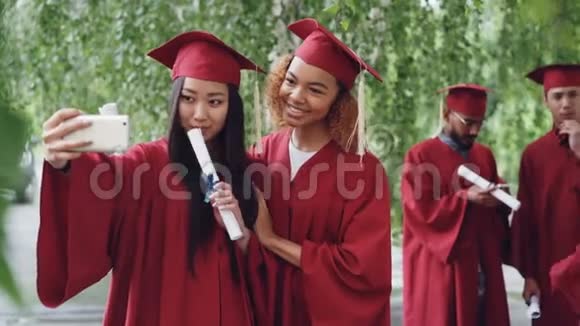 两位有魅力的女同学正拿着毕业证书在毕业当天自拍年轻的着视频的预览图