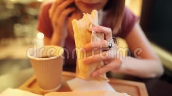 嬉皮士女孩正在吃一个美味多汁的鸡肉甜甜圈与茶玩得很开心视频的预览图