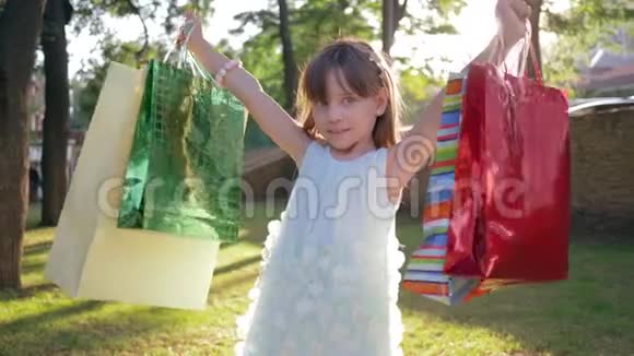 儿童购物小女孩买家喜欢新购买的包装并举手公园视频的预览图