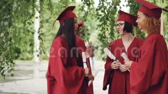 毕业典礼结束后同学们都在谈笑风生拿着毕业证书穿着长袍和灰泥板视频的预览图